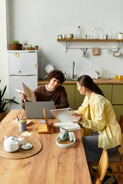 Um homem e uma mulher apreciam a companhia um do outro enquanto colaboram em um projeto em sua mesa de jantar. — Fotografia de Stock