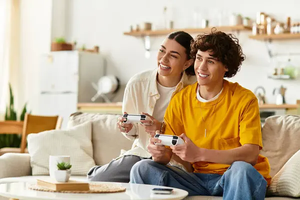 Casal sorri alegremente enquanto joga jogos de vídeo juntos no sofá em sua casa — Fotografia de Stock
