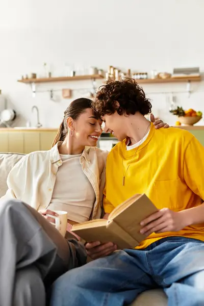 Casal compartilhando um momento terno no sofá, absorvido em um livro em sua casa aconchegante. — Fotografia de Stock