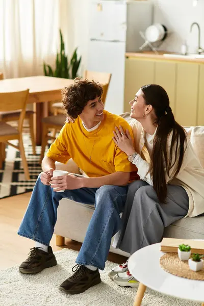 Couple relaxes together in a warm living room, sharing smiles and loving glances over coffee. — Stock Photo