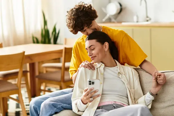 A man embraces a woman on a couch as they share a joyful moment at home, surrounded by warmth. — Stock Photo