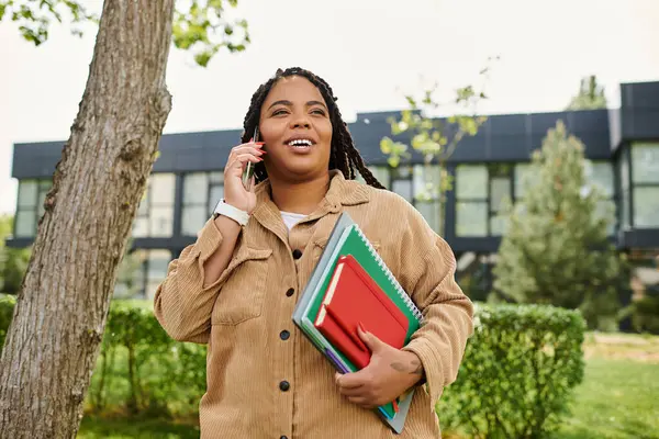 Un insegnante universitario gode di una telefonata all'esterno, portando quaderni, mostrando il suo spirito gioioso. — Foto stock