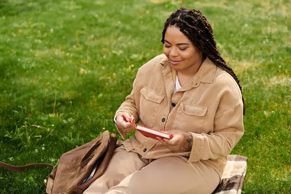 Un professeur d'université s'assoit sur l'herbe, souriant en lisant un livre sous le soleil chaud. — Photo de stock