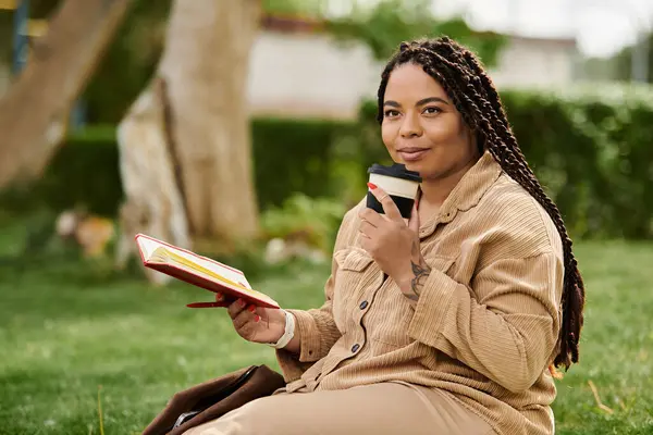 A university teacher relaxes in a park, sipping coffee while reading a book on a sunny afternoon. — Stock Photo