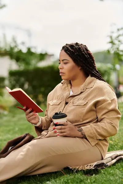 Profesora universitaria se relaja en un día soleado, leyendo un libro y tomando café en un tranquilo jardín. - foto de stock