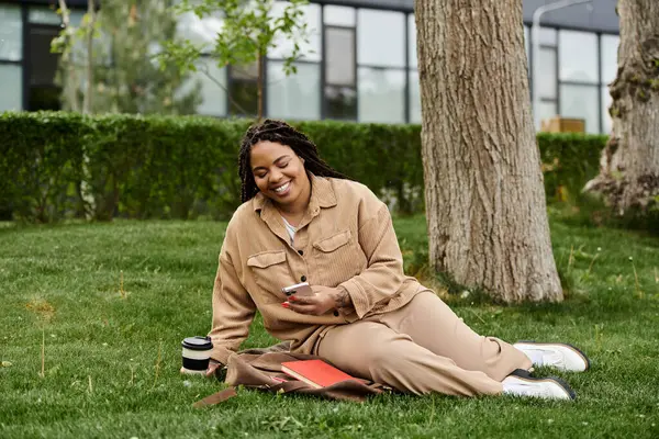 Un insegnante universitario si rilassa sull'erba, godendo il suo telefono durante una pausa tranquilla. — Foto stock