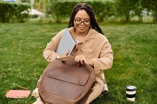 A dedicated teacher organizes her materials on lush green grass, surrounded by nature. — Stock Photo