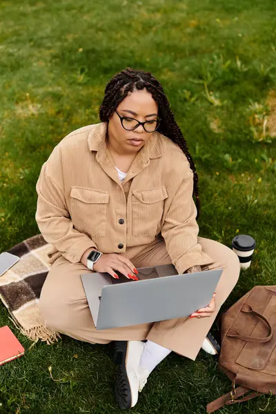 Woman teaching university students while working on a laptop in a green outdoor setting. — Stock Photo