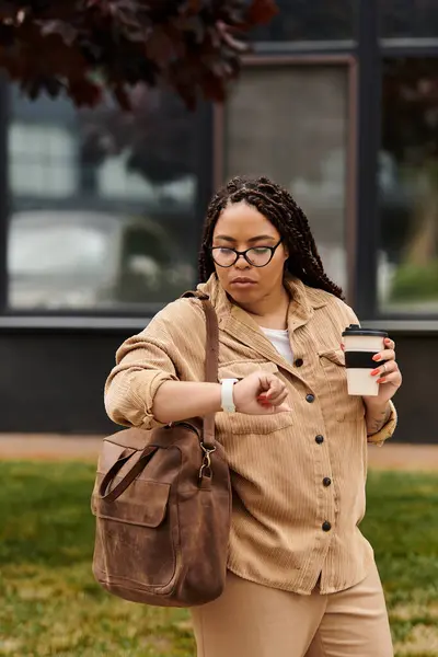 A university instructor glances at her watch, coffee in hand, amidst campus greenery. — Stock Photo