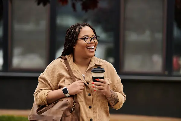 University teacher smiles while holding a coffee cup and carrying a bag on campus — Stock Photo