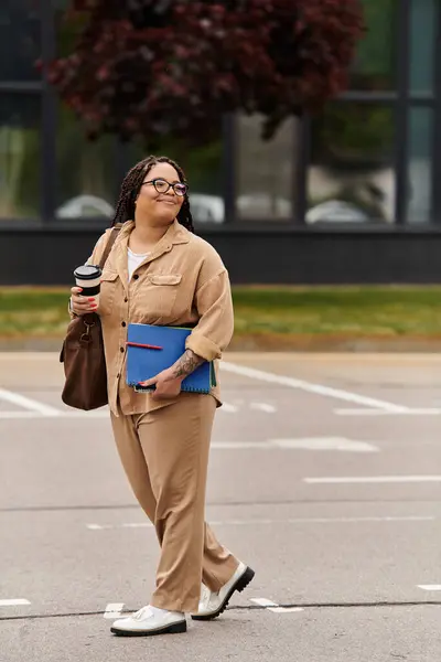 Mujer camina con confianza a través del campus, sosteniendo el café y listo para el día de la enseñanza por delante. - foto de stock