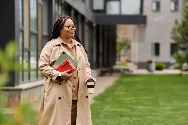 A university educator walks the campus, sipping a warm drink and carrying study materials. — Stock Photo