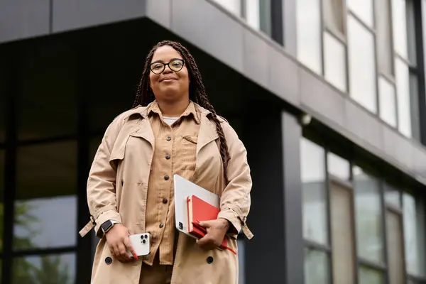 Femme éducatrice dévouée détient du matériel pédagogique tout en se tenant à l'extérieur de la structure universitaire. — Photo de stock