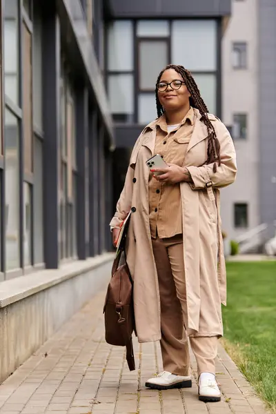 Insegnante universitario passi lungo una passerella, tenendo un telefono e una borsa, indossando abbigliamento elegante. — Foto stock