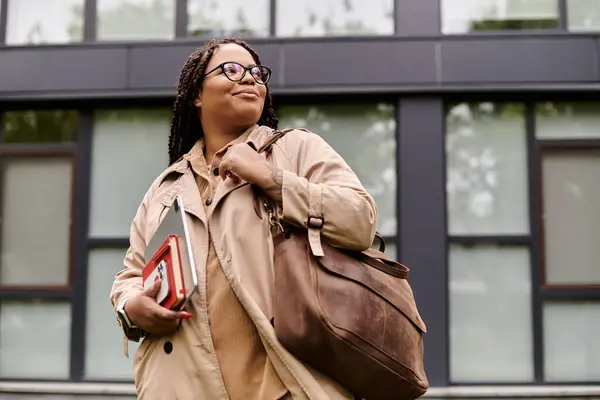 Professeur d'université se promène en toute confiance sur le campus, tenant des livres et un sac élégant tout en souriant. — Photo de stock