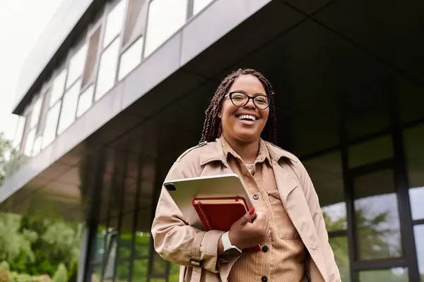 A happy university teacher walks with a tablet outside a modern educational building. — Stock Photo