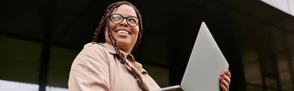 Smiling educator holds a laptop while interacting with students in the sunny campus area. — Stock Photo