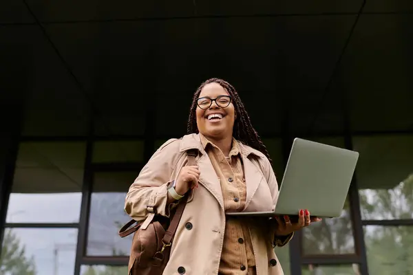 A joyful university teacher holds a laptop while interacting cheerfully with students outdoors. — Stock Photo