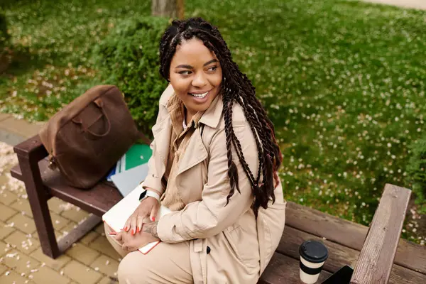 A university teacher smiles on a bench, reviewing lesson plans with coffee in hand. — Stock Photo