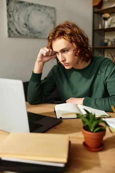A young man focuses on his work at a wooden table in a cozy home atmosphere. — Stock Photo