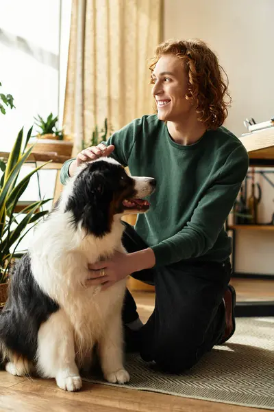 A young man joyfully plays with his dog in a bright, plant filled living space. — Stock Photo