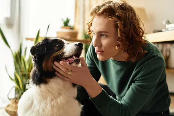 A young man enjoys a tender moment with his dog in a warm and inviting living space. — Stock Photo