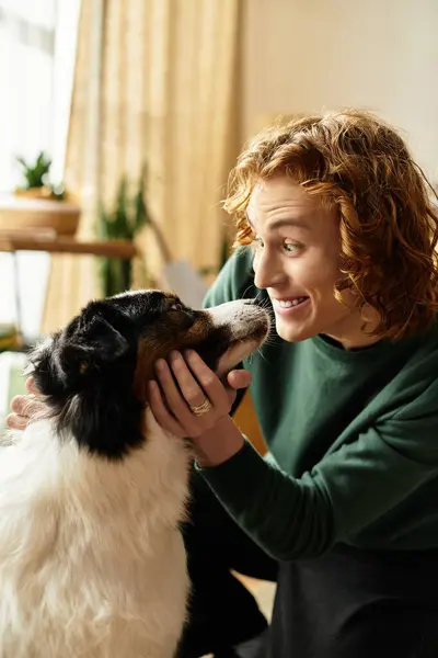 Giovane gioioso sta legando con il suo cane in uno spazio di vita caldo e invitante pieno di luce. — Foto stock