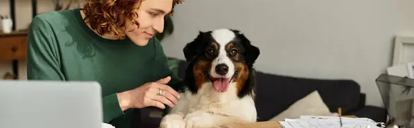 Un joven interactúa juguetonamente con su perro mientras se relaja en casa, creando un ambiente cálido. - foto de stock