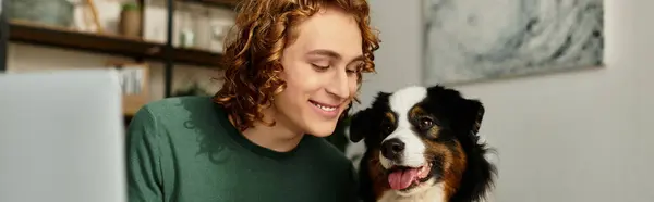 A young man smiles warmly as he sits at home with his beloved dog, creating a cozy atmosphere. — Stock Photo