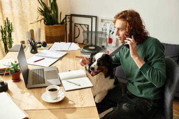 Ambiente acogedor de un joven que trabaja desde casa con su perro a su lado, comprometido en la conversación. - foto de stock
