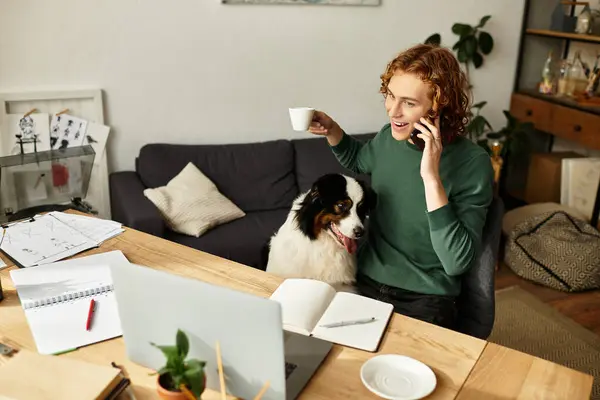 Um jovem sentado em casa se envolve em um telefonema enquanto desfruta de uma xícara quente de café. — Fotografia de Stock