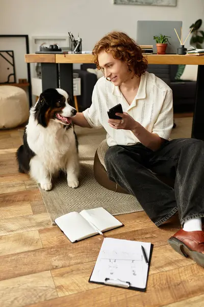 Relaxing in a comfortable space, a young man interacts with his dog while jotting down thoughts. — Stock Photo