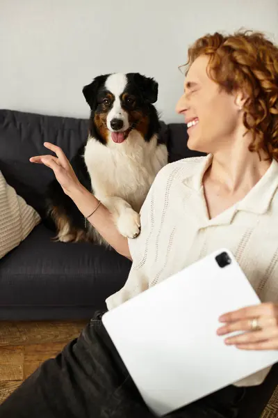 A young man relaxes with his dog on the couch, smiling and enjoying a carefree moment. — Stock Photo