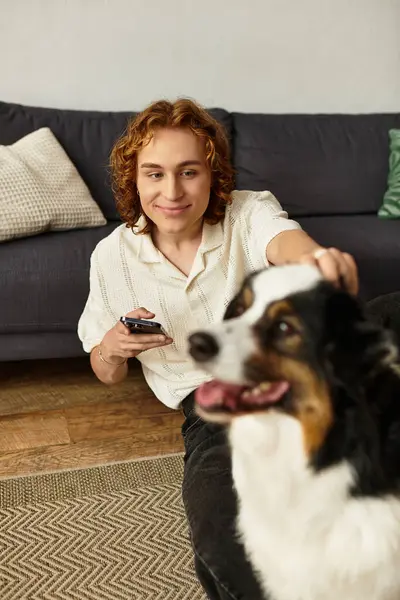 Young man relaxes on the floor, enjoying quality time with his friendly dog in a cozy home setting. — Stock Photo
