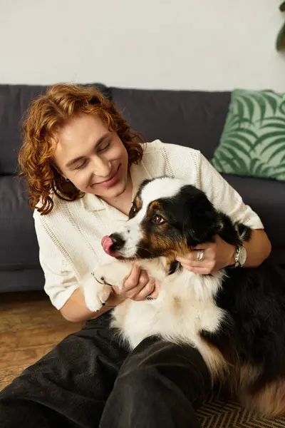 Um jovem desfruta de um tempo de qualidade em casa, se unindo com seu cão carinhoso em um espaço quente. — Fotografia de Stock