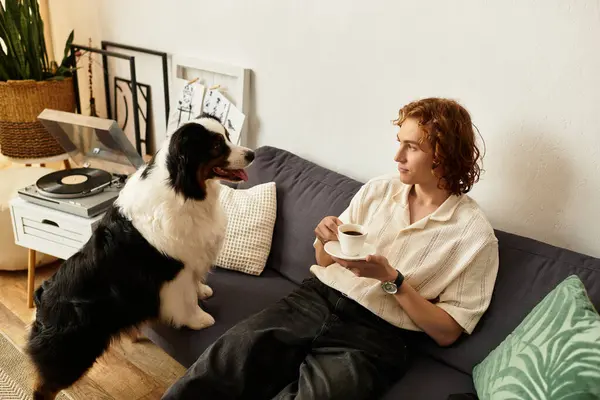 Um jovem relaxa em casa com seu cachorro, tomando café e aproveitando seu tempo juntos. — Fotografia de Stock