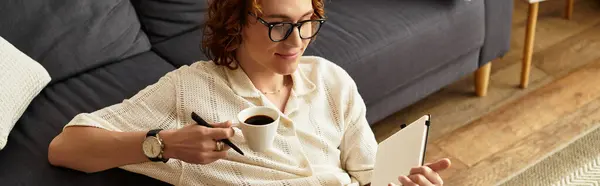 Un jeune homme se détend chez lui, sirotant un café et notant ses pensées dans un cahier.. — Photo de stock