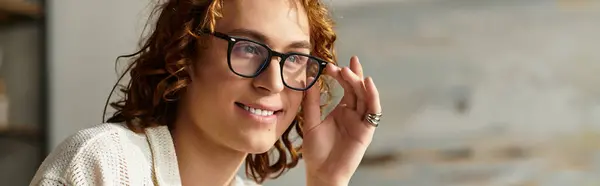 A young man with curly hair and glasses looks relaxed at home, lost in contemplation. — Stock Photo