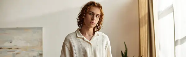 In a comfortable setting, a young man stands calmly, exuding charisma and warmth. — Stock Photo