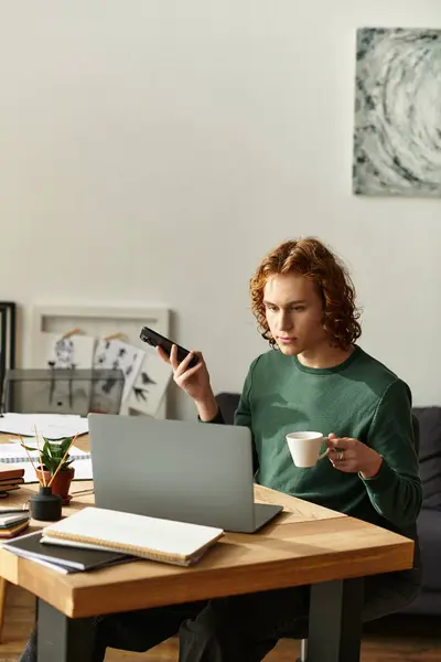 Bello giovane uomo si impegna nel lavoro dal suo ambiente confortevole casa, tenendo una tazza di caffè. — Stock Photo