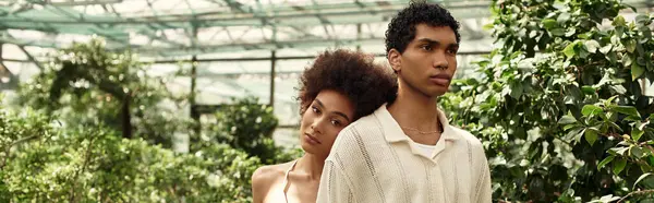 A young couple shares a tender embrace amidst vibrant plants, radiating love and connection. — Stock Photo