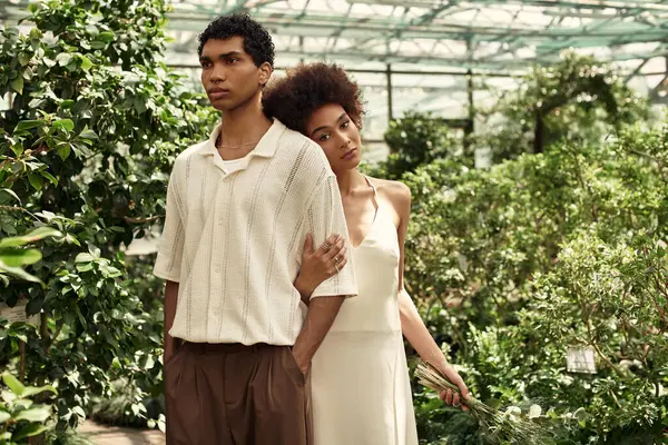 Joyful couple embraces in a greenhouse filled with flourishing plants and vibrant greenery. — Stock Photo