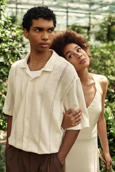 Young couple embraces in a lush greenhouse, showcasing their affection amid flourishing plants. — Stock Photo