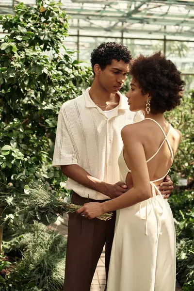 A young couple shares a romantic moment in a lush, beautiful greenhouse. — Stock Photo