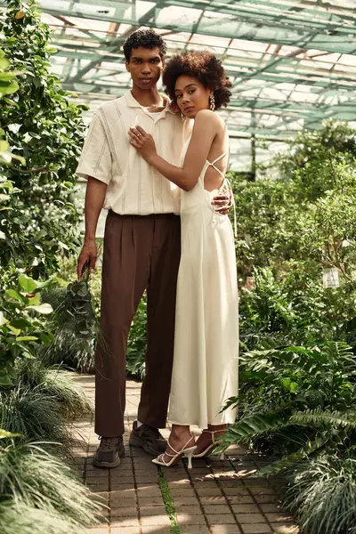 In a lush greenhouse, a young couple embraces, filled with love and romance. — Stock Photo