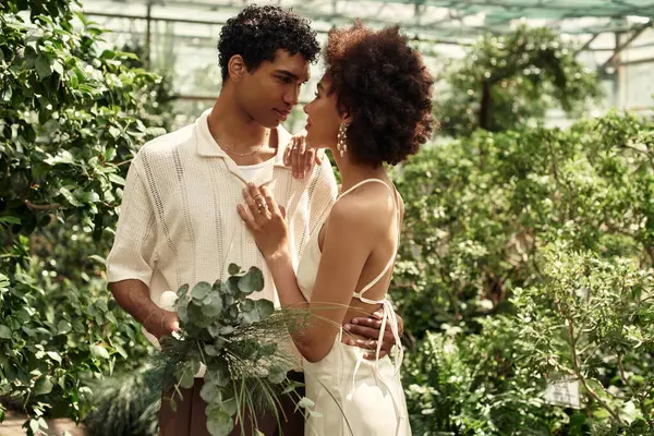 Young couple embraces tenderly amid the greenery, surrounded by thriving plants and fresh air. — Stock Photo