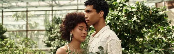 Um jovem casal se abraça em uma estufa repleta de plantas exuberantes, mostrando seu amor. — Fotografia de Stock