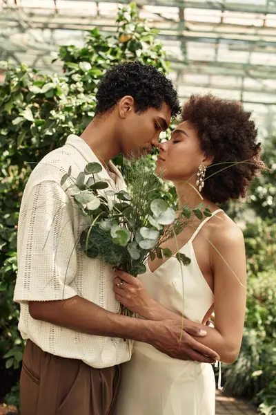 In a vibrant greenhouse, a young couple shares their love amid lush plants. — Stock Photo