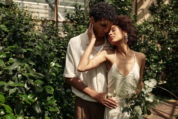 In a serene greenhouse, a young couple embraces, surrounded by lush plants and tranquility. — Stock Photo