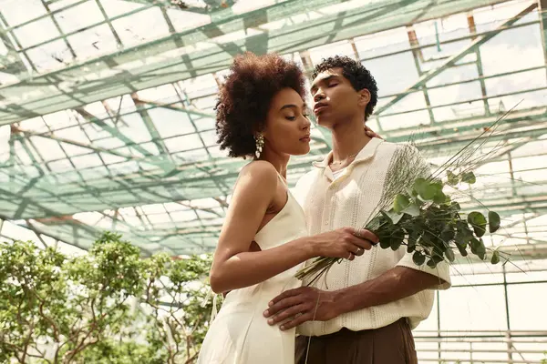 Em uma estufa serena, um casal abraça, cercado por plantas vibrantes e uma atmosfera tranquila. — Fotografia de Stock